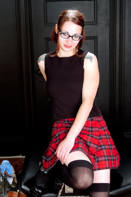Сильно татуированная рыжая девушка снимает наряд школьницы в черных носках проститутки