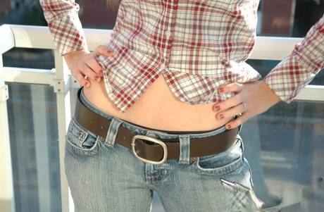 Redheaded country girl models non nude in tied up shirt and denim jeans
