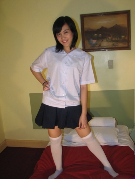 Asiatisk skolepige blotter trusser under skørtet, før hun bliver nøgen i OTK-strømper