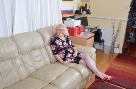 Une vieille dame britannique en lingerie et en bas de nylon se fait plaisir avec un vibrateur.