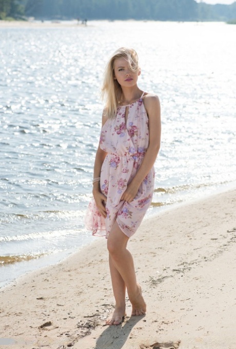 Un mannequin solo blonde enlève sa robe et sa culotte à la plage.
