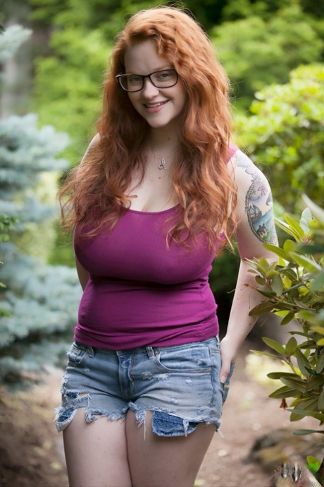 Une adolescente rousse naturelle expose son corps épais et ses gros seins tombants dans les bois.