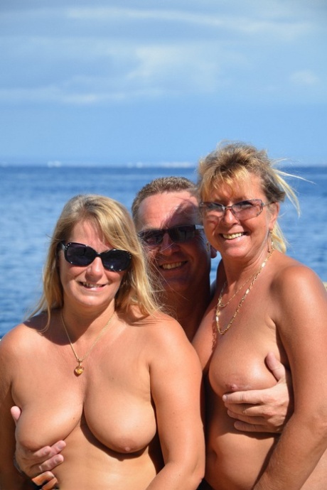 Duas mulheres loiras com mamas descaídas gostam de chupar e foder em trio na praia