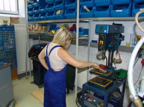 Mature blonde removes her overall before masturbating in workshop