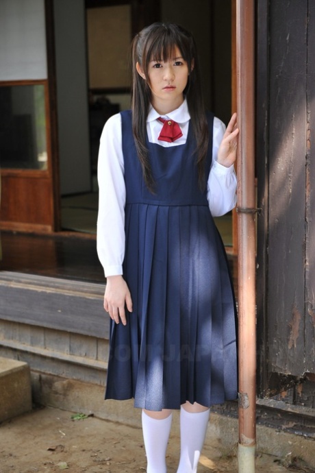 Очаровательная японская малышка позирует в своем милом школьном наряде в саду