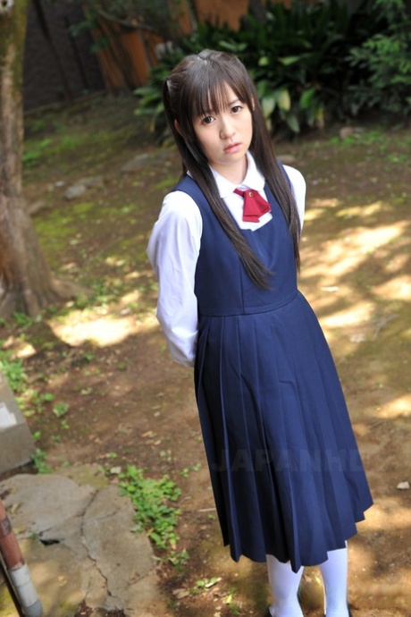 Очаровательная японская малышка позирует в своем милом школьном наряде в саду