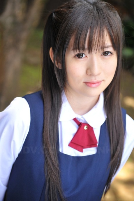 Charmante jeune fille japonaise posant dans sa jolie tenue d'écolière dans le jardin.