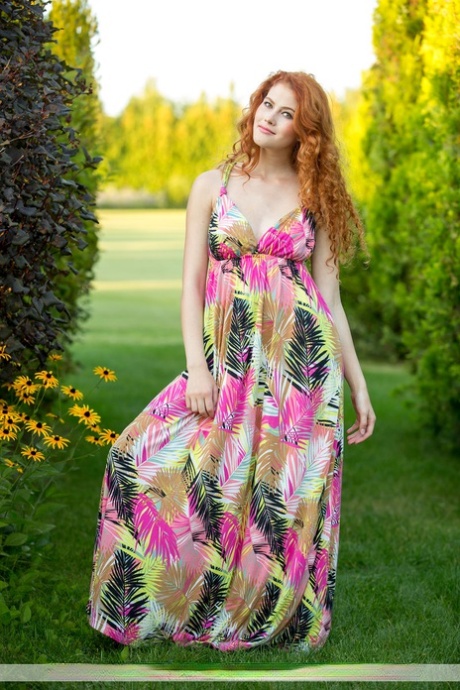 La belle rousse Heidi Romanova enlève sa longue robe pour poser nue sur la pelouse.