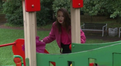 Ładna dziewczyna Oksana kucnęła, aby się odlać na placu zabaw w parku publicznym