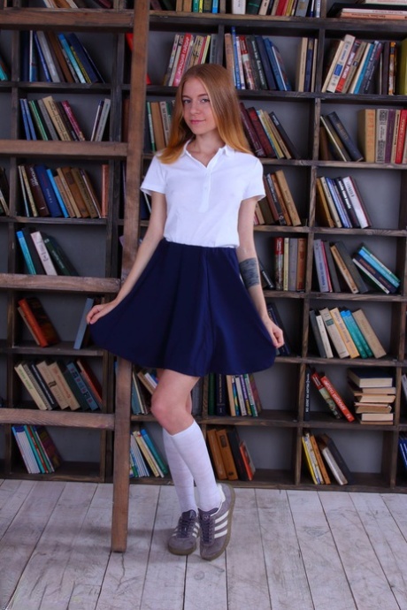 Den slanke skolejenta Chloe kler av seg til knestrømper foran bokbunken.