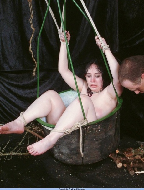 Overvektig kvinnelig sexslave holdes fast i en kurv under nålelek.
