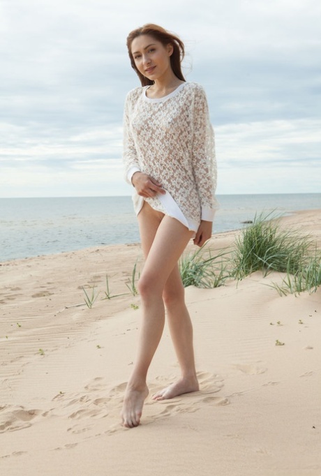 Young beauty Lena Raz gets completely naked on a sandy beach