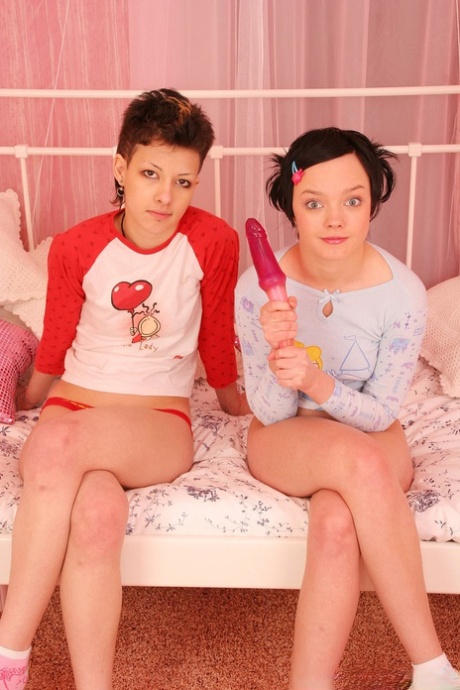 Young looking girls use a sex toy during lesbian sex on a daybed