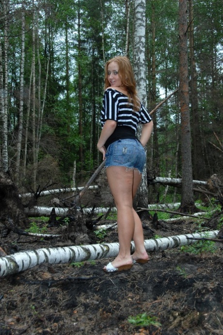 性感的红发女郎在森林中展示她的小奶子和大屁股