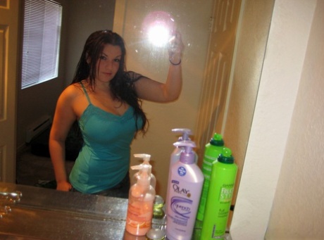 Amateur solo girl takes self shots of her big breasts in a bathroom mirror