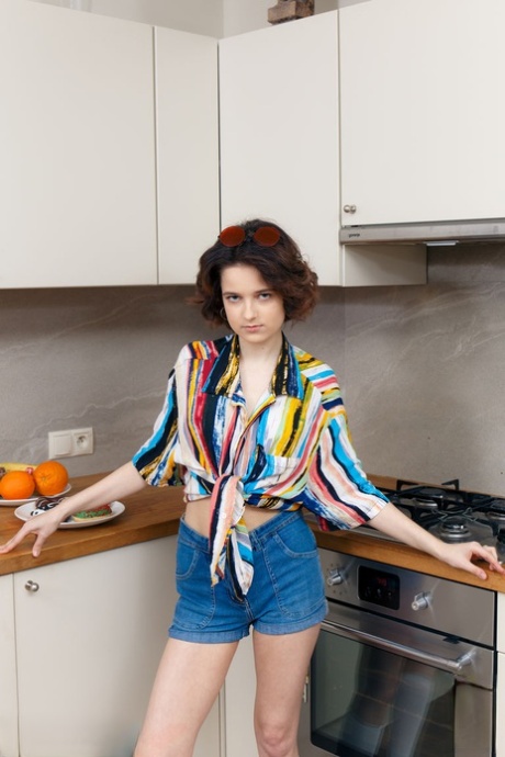 Tiener Polyna staat naakt in de keuken terwijl ze donuts eet