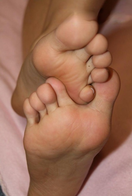 Unknown Caucasian female gently rubs her pretty feet together