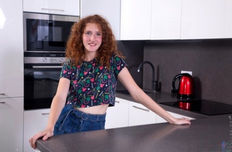 Подростковая соло девушка Фокси Ли демонстрирует кудрявые рыжие волосы, раздеваясь на кухне