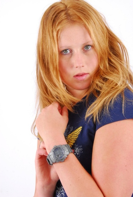 Přírodní zrzka Judy ukazuje své šedé hodinky G-Shock v tričku a džínách