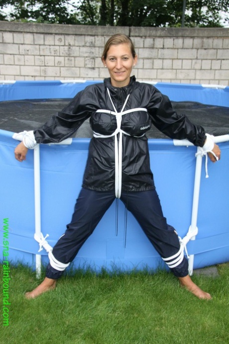 Amateur woman Sandra is gagged and tied to a pool in a raincoat