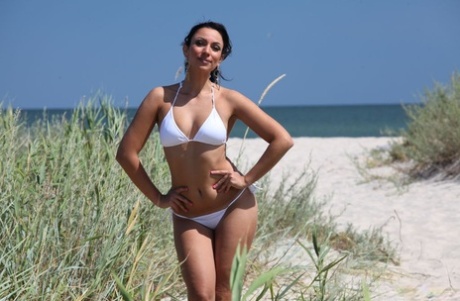 Lusse i sin vita bikini leker med sanden med solkyssta hennes randiga och