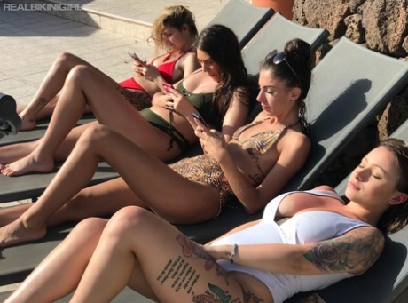 Four girls take off their bikini tops while sunbathing on lounge chairs