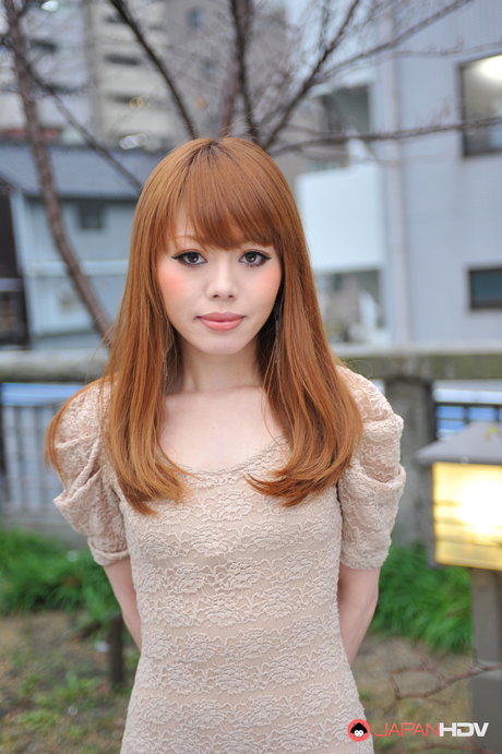 Sexy japansk jente med rødt hår, Reika Kitahara, poserer utendørs i en kort kjole.
