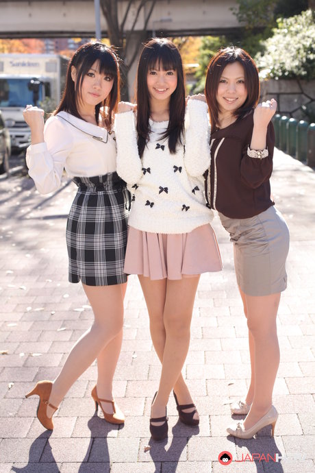 Tre japanska tjejer i kjol poserar utomhus för en SFW-fotografering