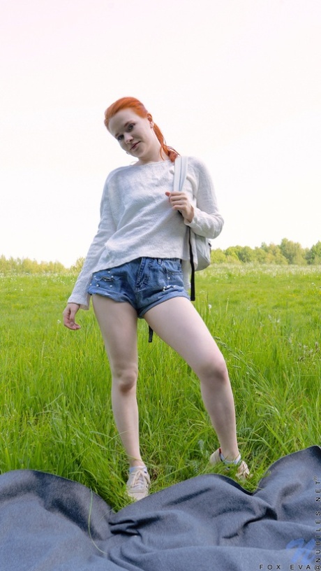 Pale redheaded teen Fox Eva gets naked on a blanket in a field