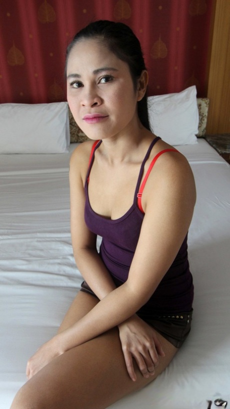 Thajská sólo dívka se váhavě svléká na posteli pro sexuálního turistu