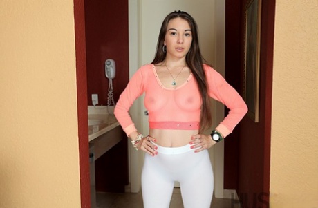Latinamerikansk kvinna i genomskinlig topp och yogabyxor visar upp sin saftiga rumpa