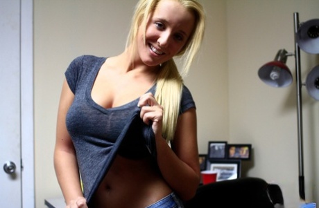 Блондинка-любительница снимает джинсы и стринги перед тем, как погладить пальцами свою подростковую киску