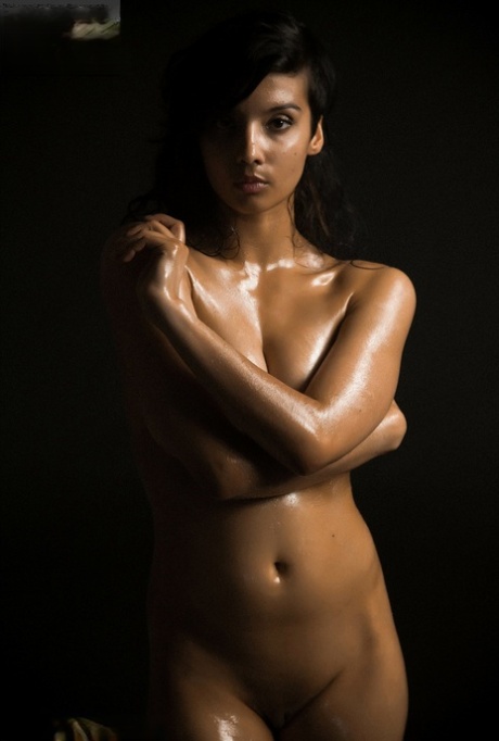 Naken indisk kvinna blottar ett enda bröst när hon står modell i mörkret