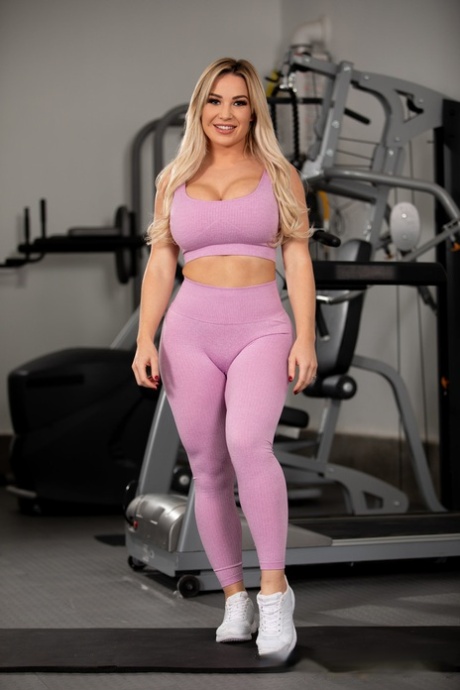 Blonde vrouw Amber Jade toont haar grote tieten en enorme kont in de sportschool