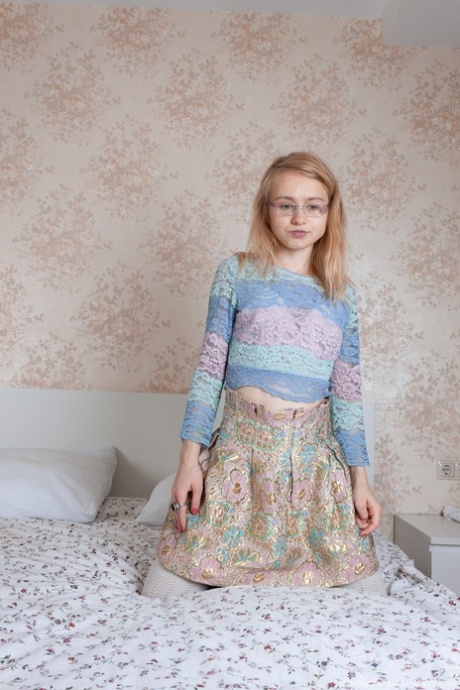 Süßes zierliches Teenie mit Brille Lightfairy stellt ihre haarige Vagina auf einem Bett zur Schau