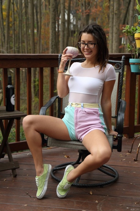 Uśmiechnięta nastolatka Daisy Haze wkłada butelkę wina do swojej szpilki na zewnątrz
