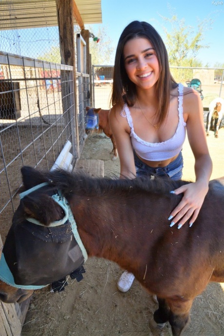 Uśmiechnięta amatorka Kylie pozuje w dżinsowych szortach i białej koszuli w zoo