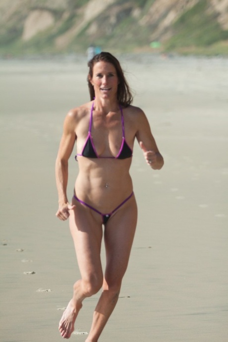 Sexy all-natural mature Sofie Marie runs on the beach in a very skimpy bikini