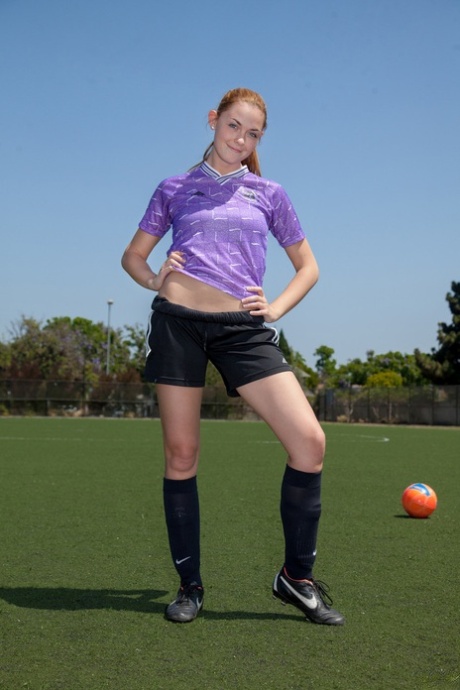 Sporty redhead teen Bailey Rayne flashes her tight ass on the soccer field