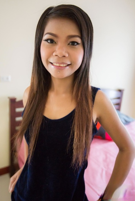Den thailandske jenta Min tar av seg klærne og viser frem den slanke figuren sin på sengen.