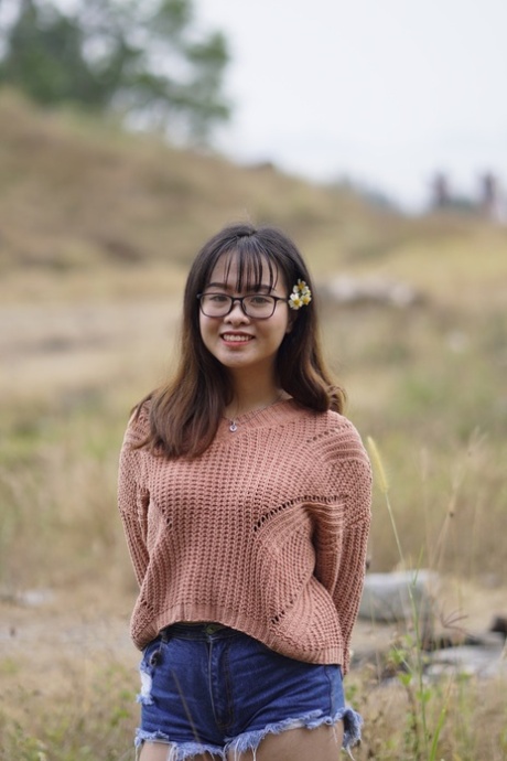 A deslumbrante rapariga asiática posa com os seus calções de ganga e camisola em público