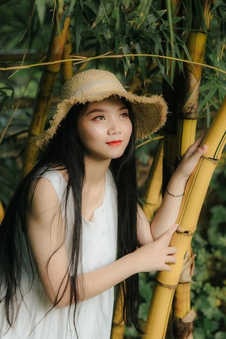 Schönes brünettes asiatisches Babe posiert in ihrem langen weißen Kleid auf dem Bauernhof